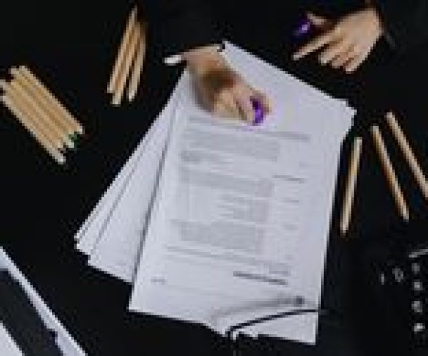 pexels photo 9655620 9655620 Hands working with documents and colored pencils on a black desk view.